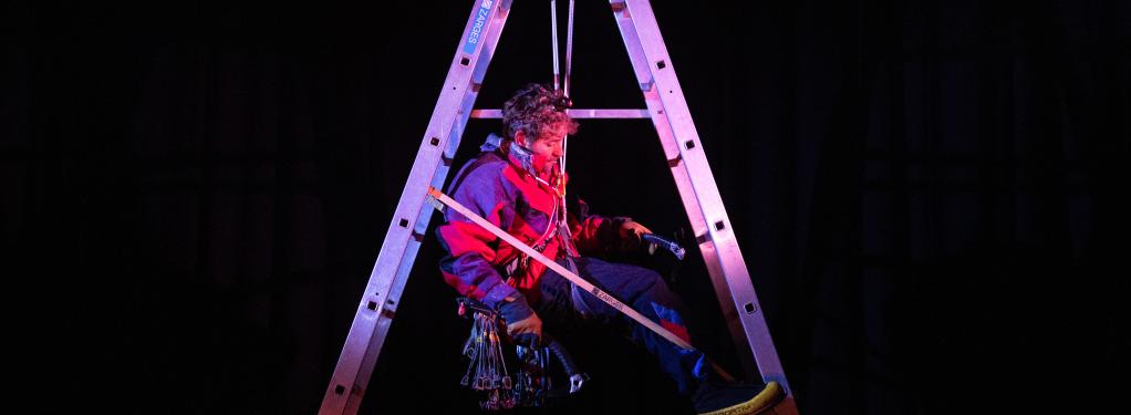 Climber hanging inside a set of ladders.